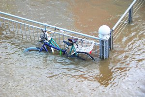 Ein angeschlossenes Fahrrad steht im Hochwasser an der Weser